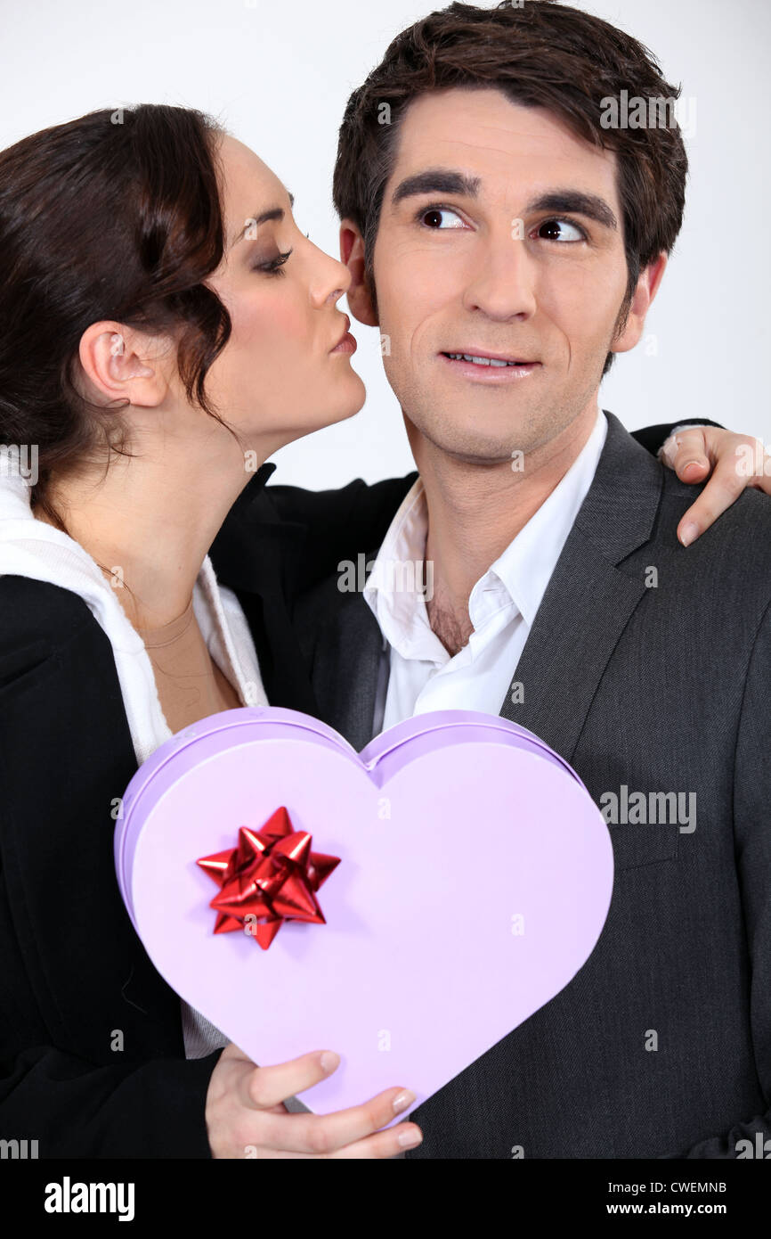 Frau küssen Mann mit Geschenk Stockfoto