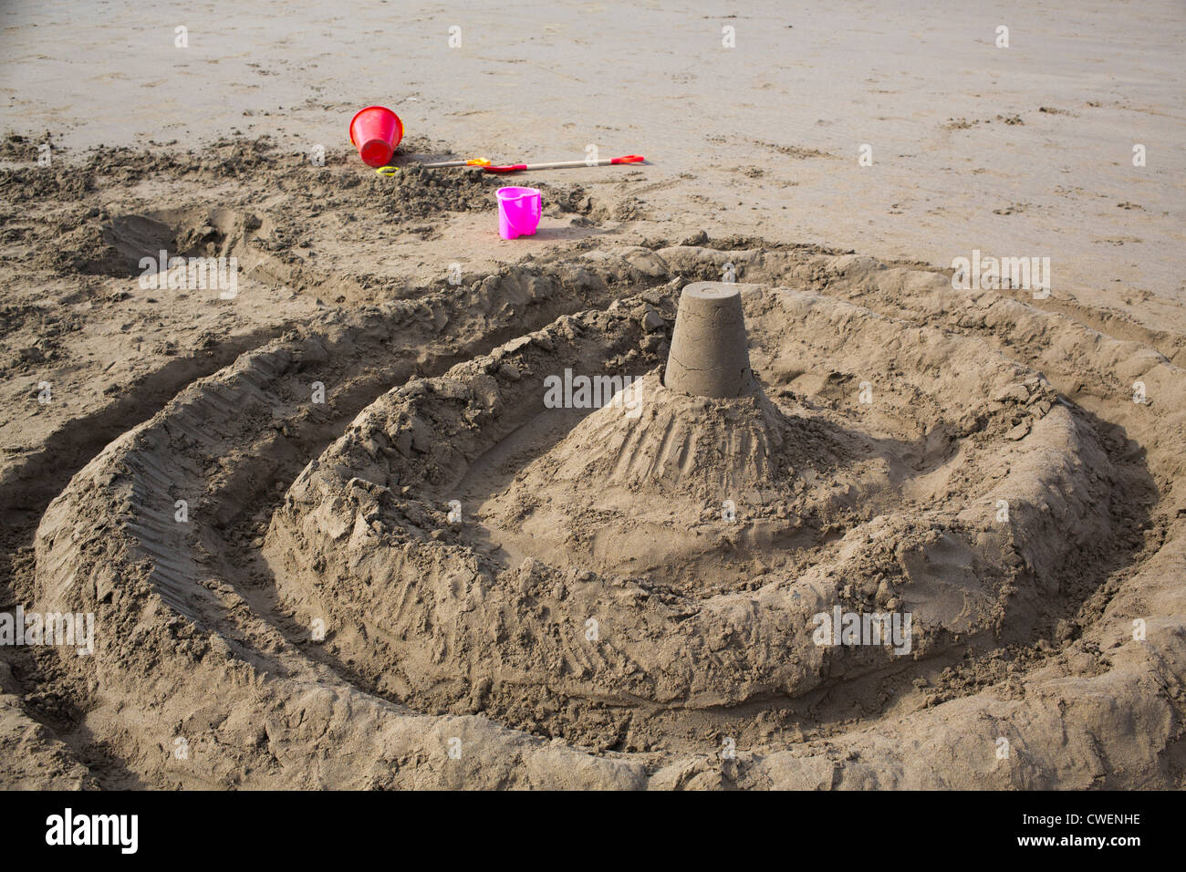Sandburg am Strand mit Wassergraben und rosa Eimer und Schaufel 121118 Sand Burg Stockfoto