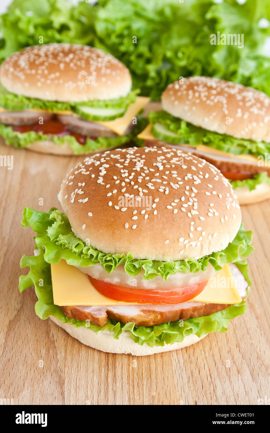 drei Hamburger mit Fleisch und Gemüse auf Holzplatte Stockfoto