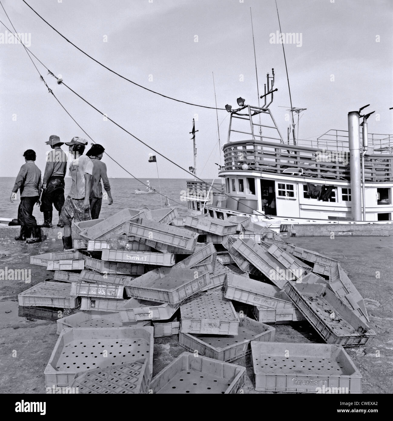 Thai Fisherman mit leeren Trays nach Entladen der täglichen Fang. Hua Hin Thailand Hafen S. E. in Asien die Schwarz-Weiß-Fotografie Stockfoto