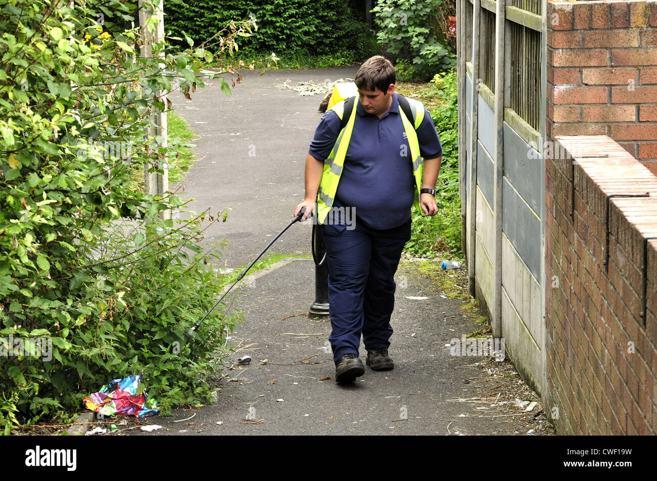 Manchester Stadtrat Mitarbeiter nutzt einen Handsprüher betriebenen Rucksack am Rand der Wanderweg Stockfoto
