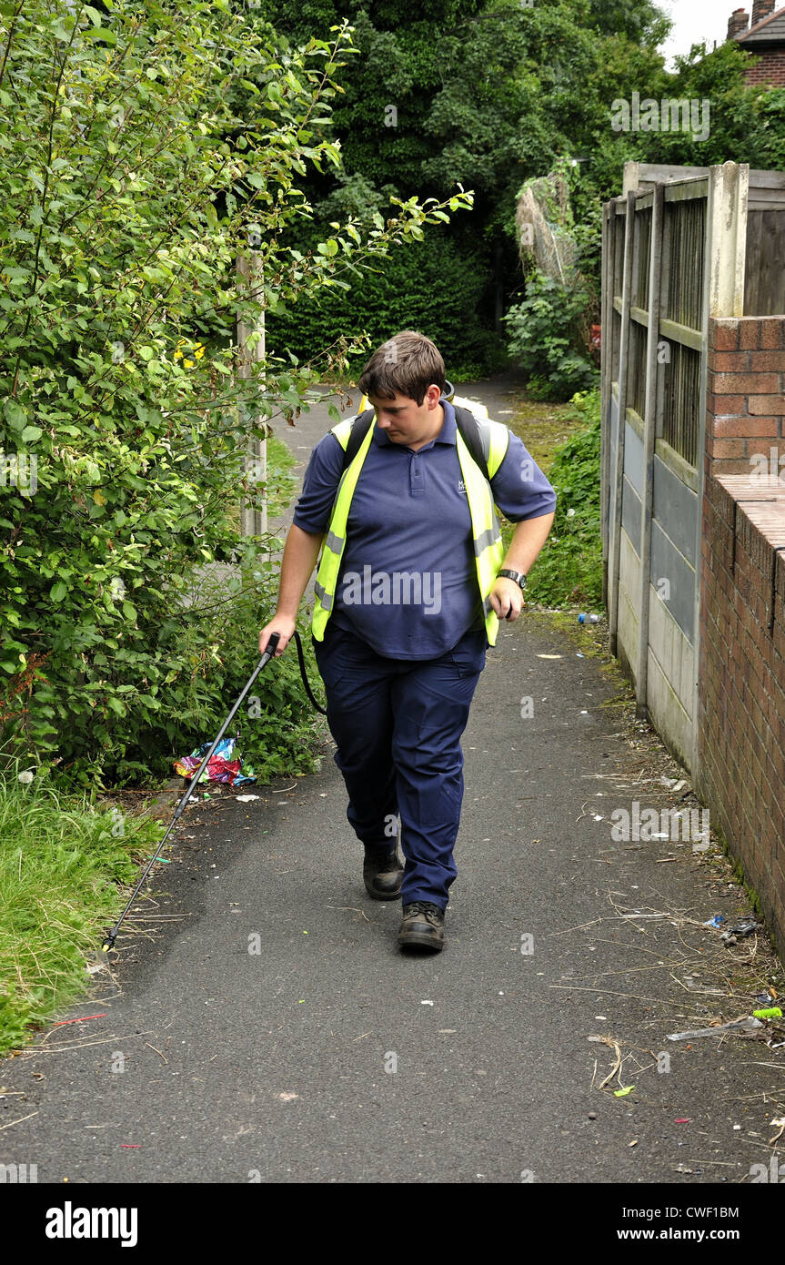Manchester Stadtrat Mitarbeiter nutzt einen Handsprüher betriebenen Rucksack am Rand der Wanderweg Stockfoto