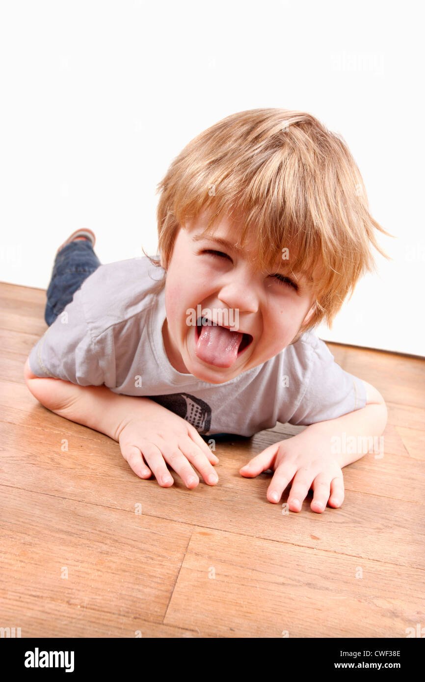Junge zieht ein lustiges Gesicht auf dem Boden spielen Stockfoto