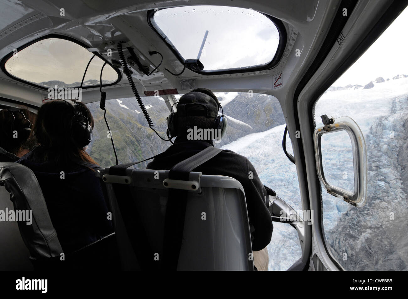 Ein paar Touristen sitzen neben dem Piloten bei einem touristischen Hubschrauberrundflug über den Franz-Josef-Gletscher in Neuseeland Stockfoto