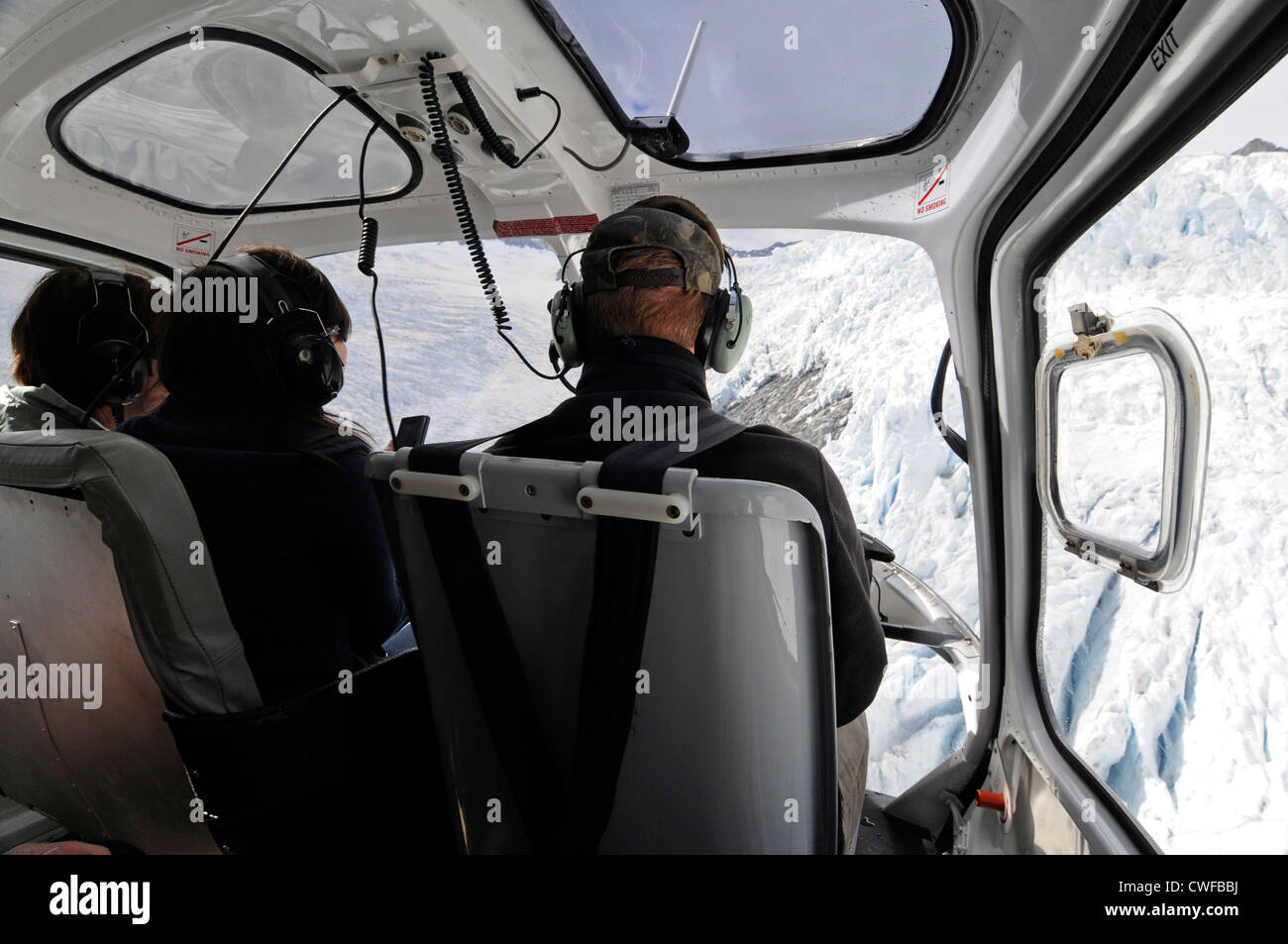 Ein paar Touristen sitzen direkt neben dem Piloten im touristischen Sightseeing Helikopterflug über Franz Josef Gletscher in Neuseeland Stockfoto