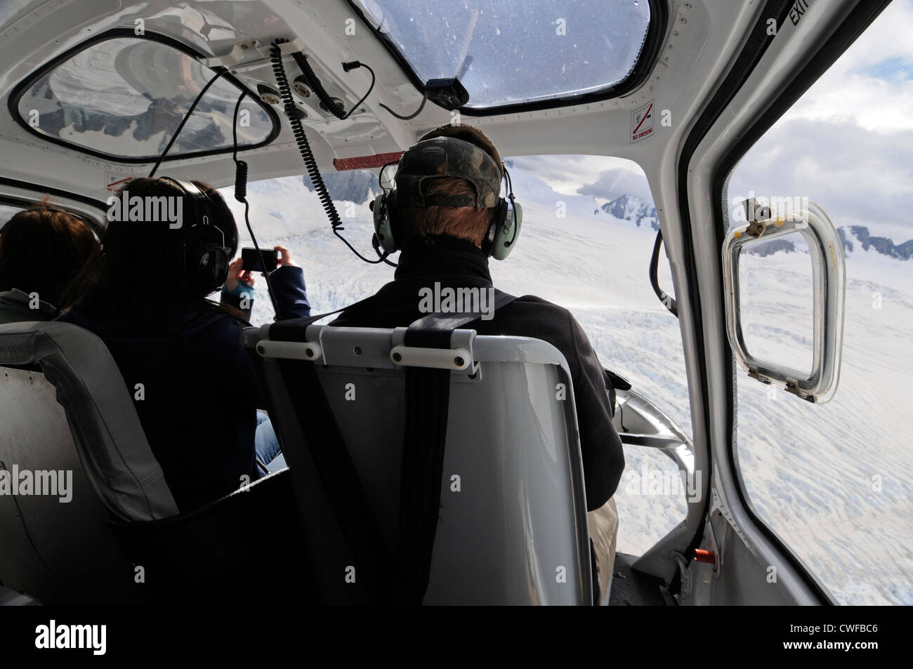 Ein paar Touristen sitzen neben dem Piloten bei einem touristischen Hubschrauberrundflug über den Franz-Josef-Gletscher in Neuseeland Stockfoto