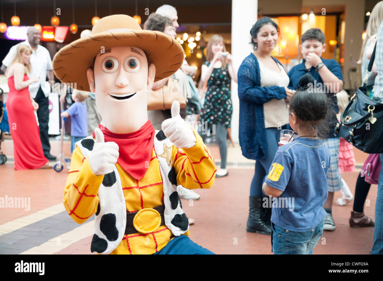 Kinderanimateurin Woody Figur aus "Toy Story", Cardiff, Wales. Kinder mit einem Mann, gekleidet wie ein Walt Disney-Figur. Stockfoto
