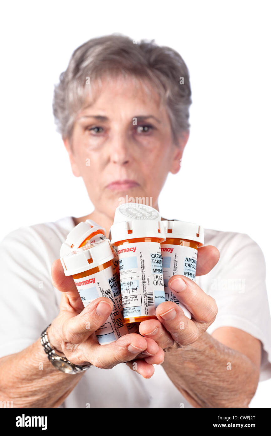 Eine ältere Frau zeigt viele Medikamente, die sie ergreifen muss, um gesund zu bleiben. Stockfoto