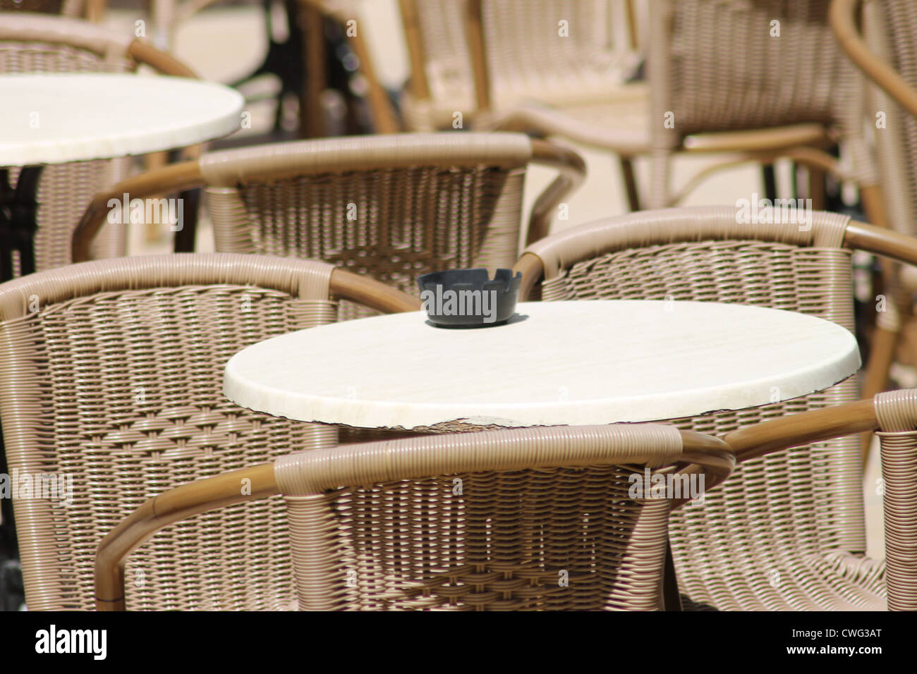 Aschenbecher am Tisch mit Korbstühlen im Freien. Stockfoto