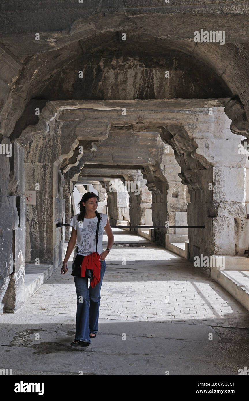 Junge Frau, die unter Bögen unter römische Amphitheater oder Arena Nimes Frankreich Stockfoto