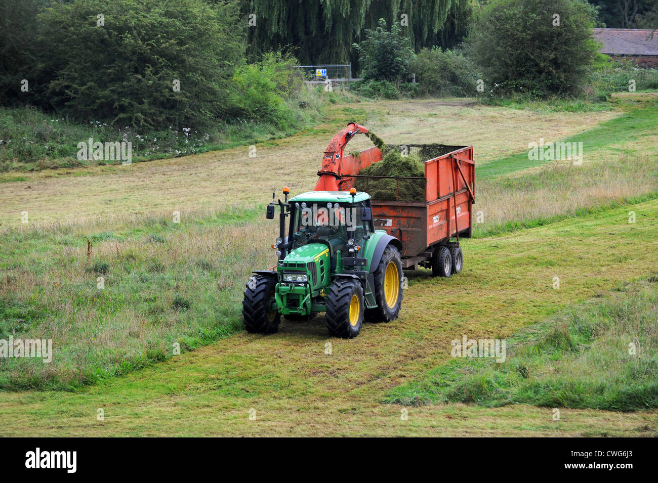 Traktor Ausschnittgras auf Wiese in Shropshire, England Uk Stockfoto