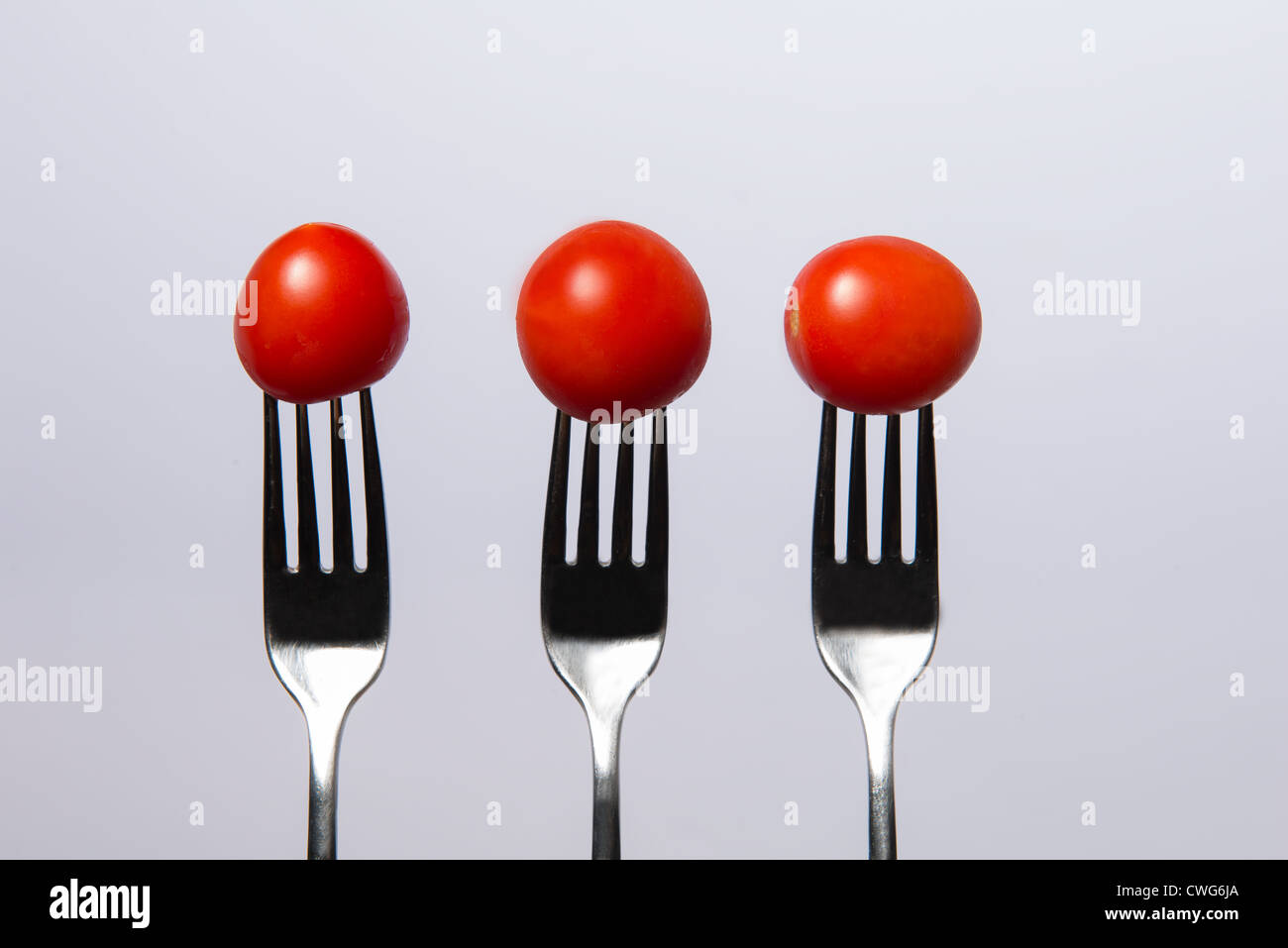 drei Gabeln und drei Tomaten Stockfoto