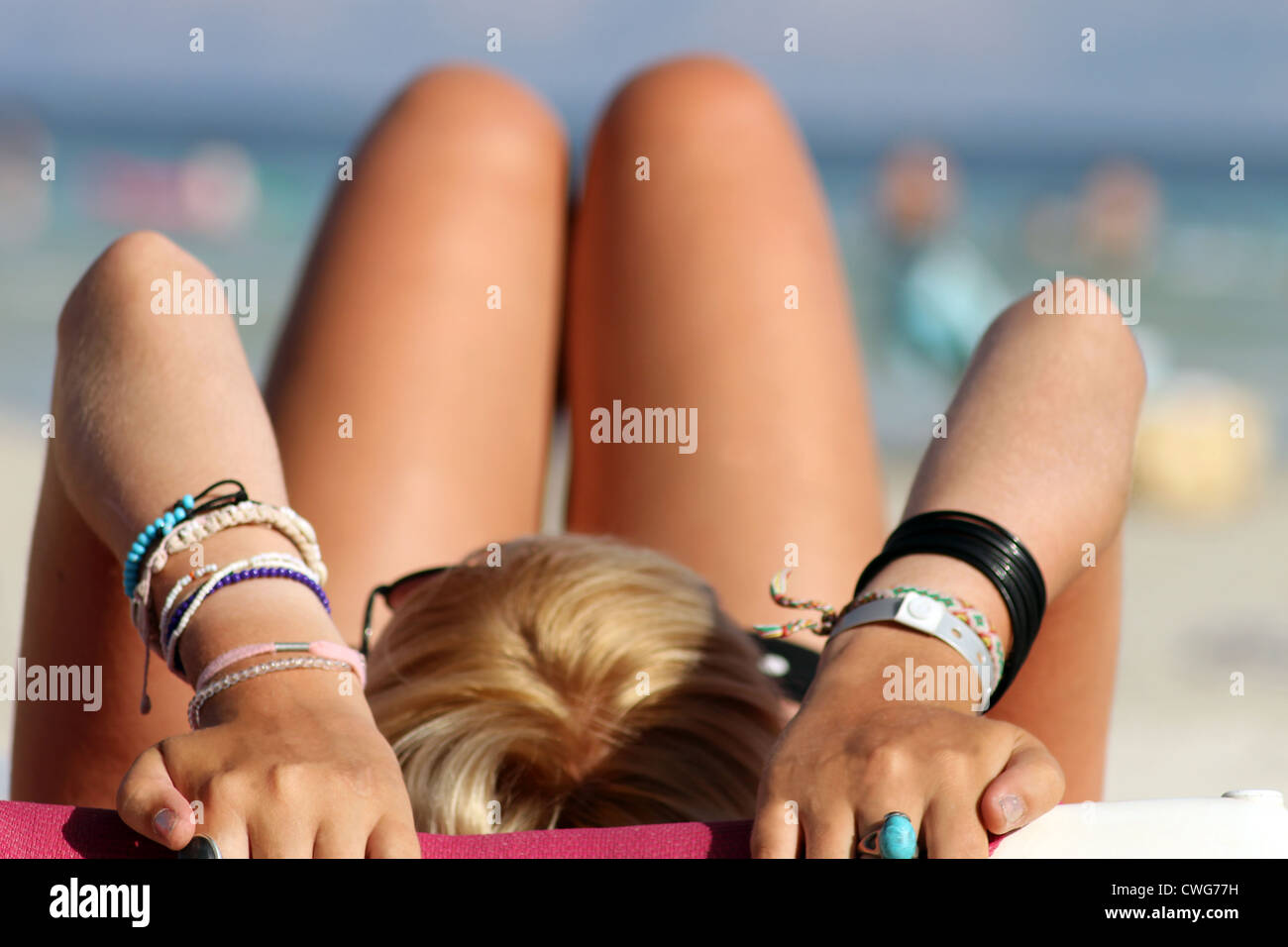 Rückansicht des blonden Mädchens Sonnenbaden am Sandstrand mit Meer im Hintergrund. Stockfoto