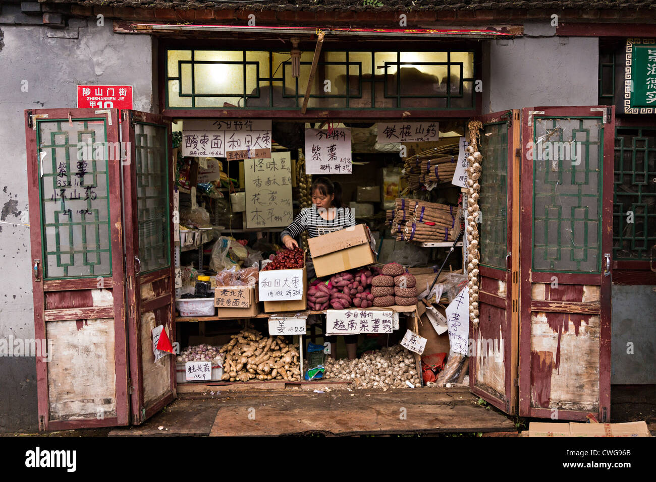 Eine Frau arbeitet in ihrem traditionellen Geschäft mit Wurzel-Gemüse entlang einem Hutong in Peking, China Stockfoto