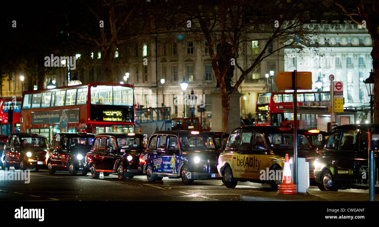 Kultigen roten Busse und Taxis auf dem Londoner Trafalgar Square in der Nacht im Regen. Stockfoto