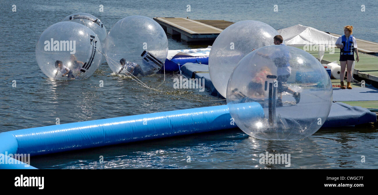 Kinder spielen in gefesselte aufblasbare Bläschen am dock Wasser bei Aqua Kugeln Anlage mit Aufpasser anwesend Stockfoto