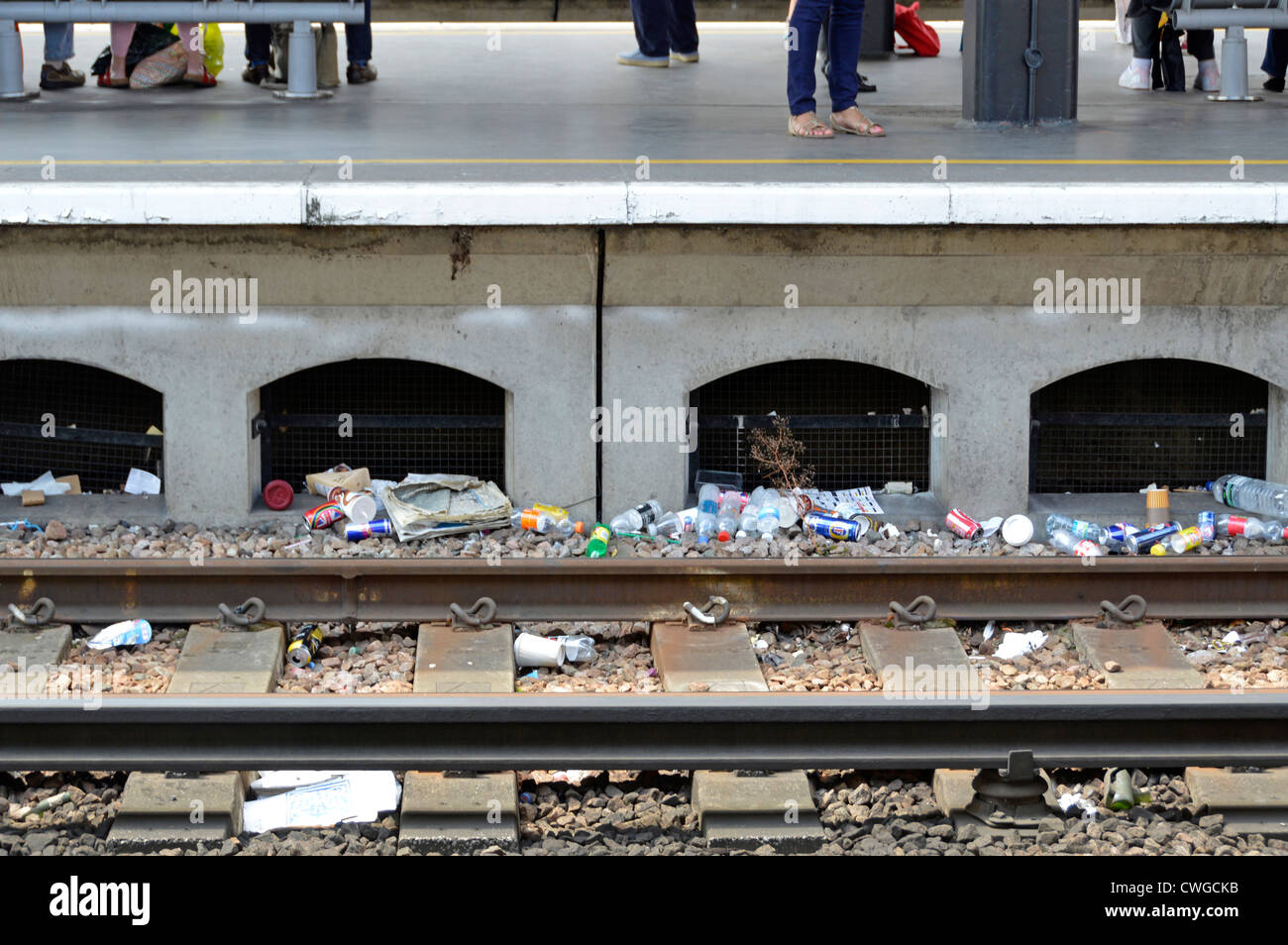 Die Menschen warten auf Bahnsteig mit Bahngleisen unterhalb von weggeworfenen Müll an der London Bridge Station England UK unkenntlich Stockfoto