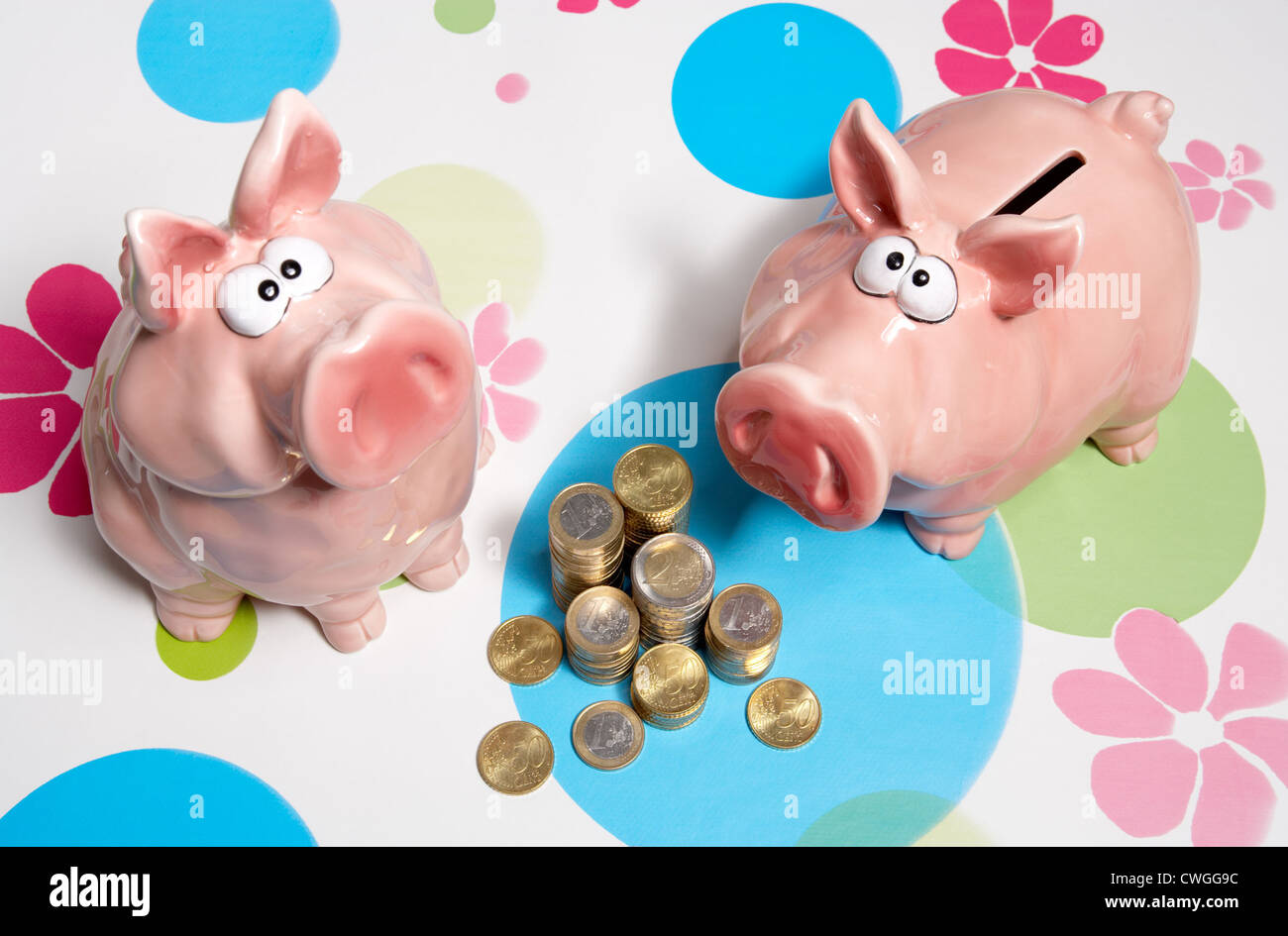 Sparschweine mit Muenzstapeln auf gemusterten Hintergrund Stockfoto