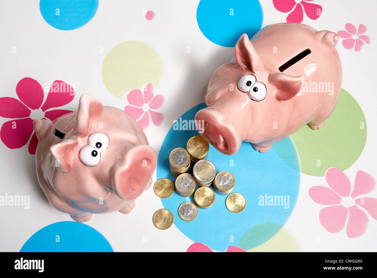 Sparschweine mit Muenzstapeln auf gemusterten Hintergrund Stockfoto