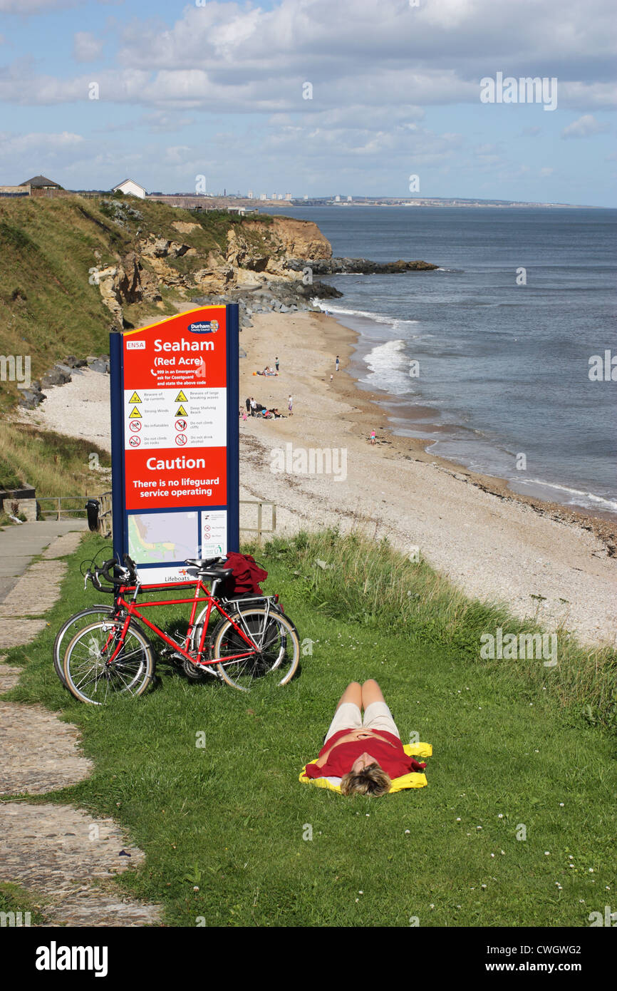 Radfahrer, die liegen auf dem Rasen ruht oberhalb des sandigen Strandes bei Seaham, Nord-Ost England UK Stockfoto