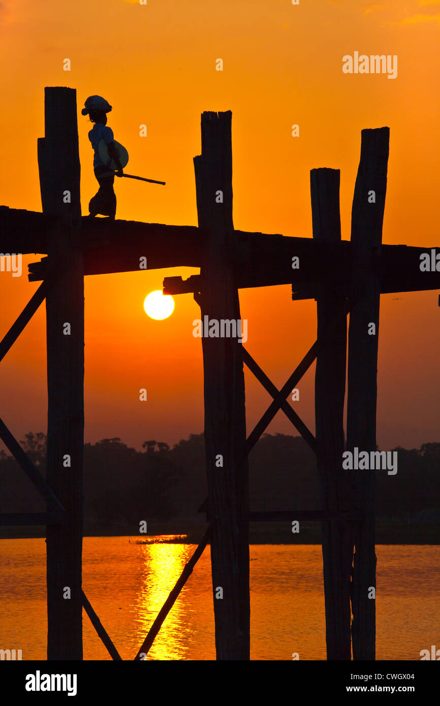 Die BURMESISCHEN Verwendung das Teakholz Brücke U KLANGKUNST um zu pendeln über den Taungthaman-See bei Sonnenaufgang - AMARAPURA, MYANMAR Stockfoto