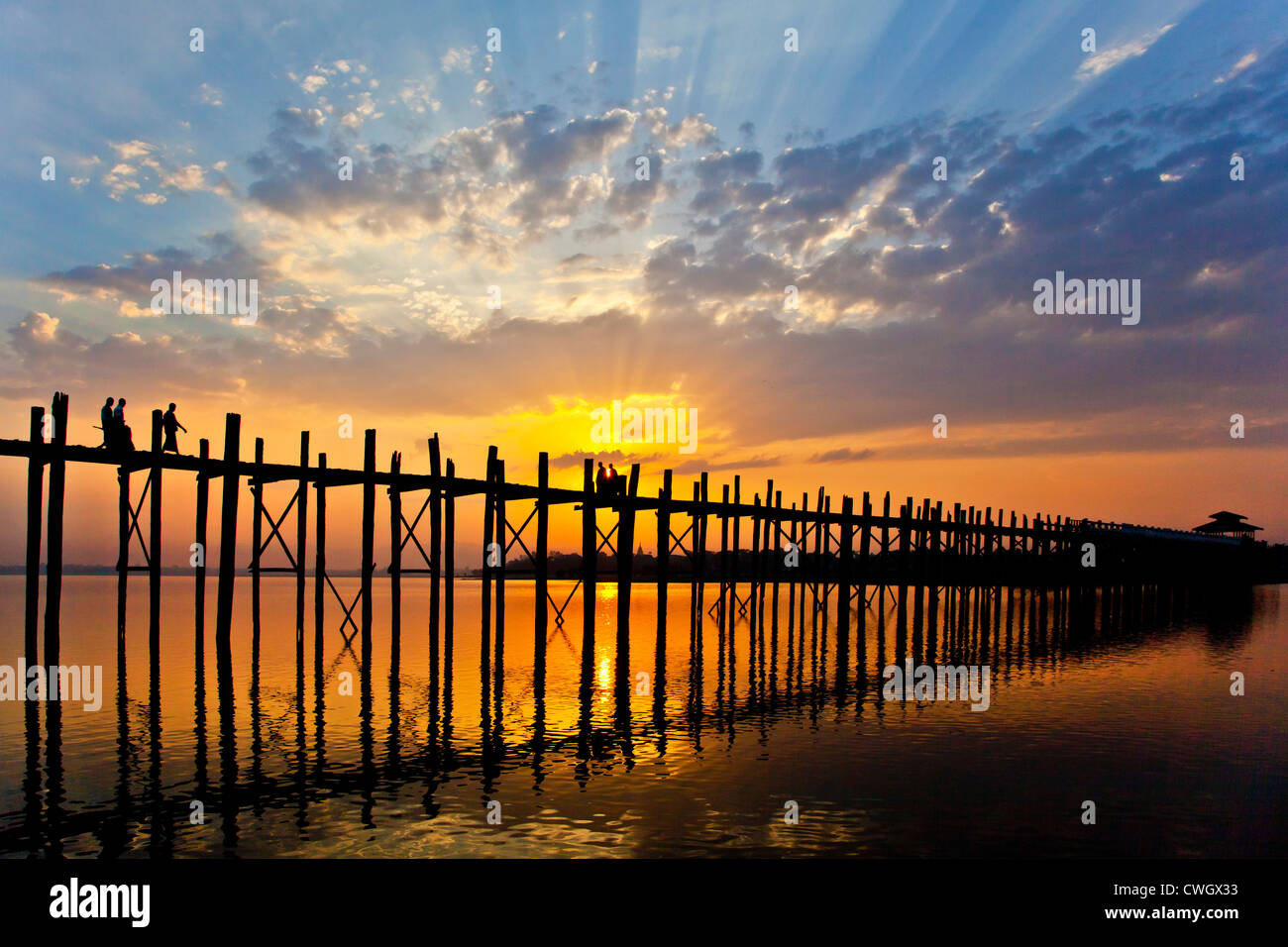 Die BURMESISCHEN Verwendung das Teakholz Brücke U KLANGKUNST um zu pendeln über den Taungthaman-See bei Sonnenaufgang - AMARAPURA, MYANMAR Stockfoto