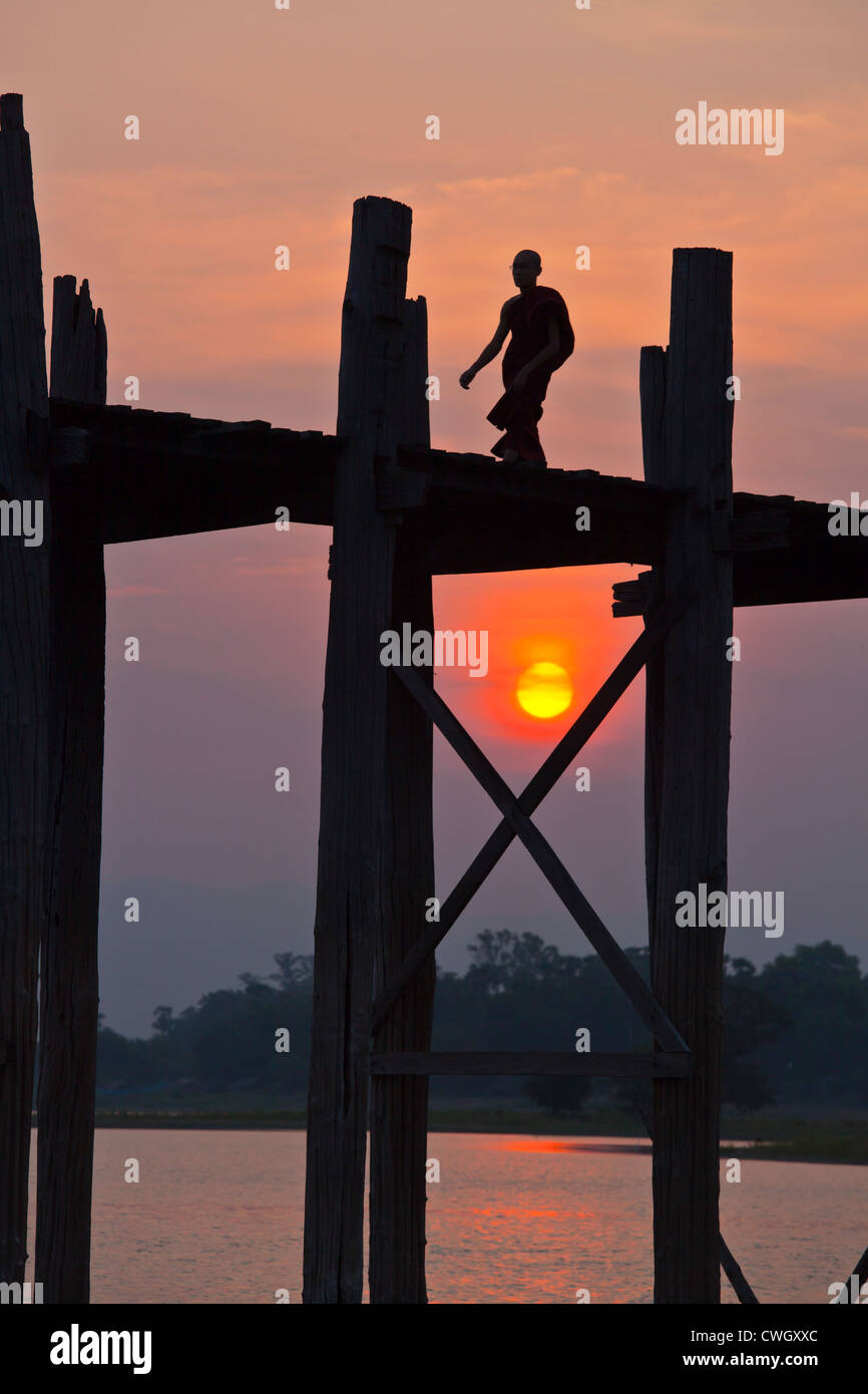 Die BURMESISCHEN Verwendung das Teakholz Brücke U KLANGKUNST um zu pendeln über den Taungthaman-See bei Sonnenaufgang - AMARAPURA, MYANMAR Stockfoto