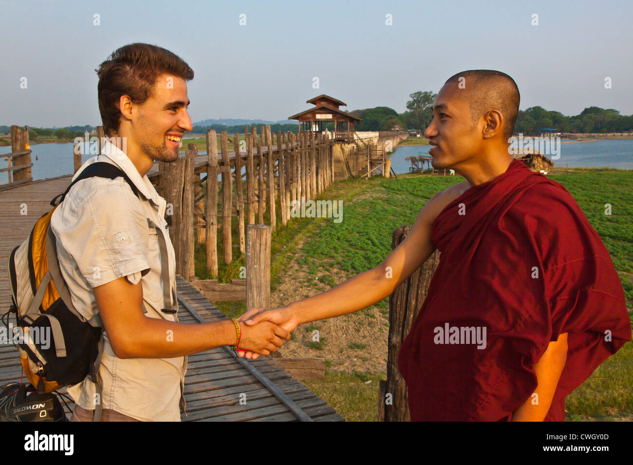 BURMESISCHE Mönch und einem französischen Touristen treffen auf das Teakholz U KLANGKUNST Brücke kreuzt Taungthaman See AMARAPURA, MYANMAR Stockfoto