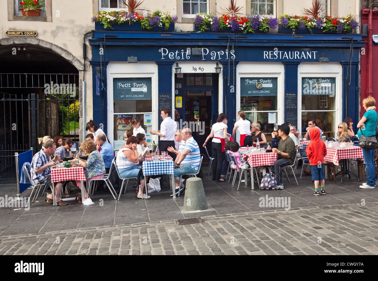 Gäste speisen auf karierten Tischdecken an Tischen außerhalb des Petit Paris, einem französischen Bistro, Restaurant, Café, Grassmarket, Edinburgh Stockfoto