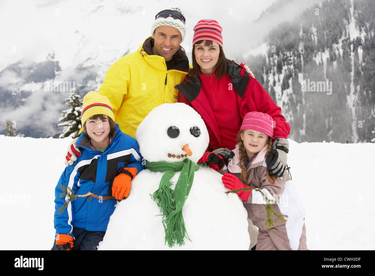 Familie Gebäude Schneemann auf Ski-Urlaub In Bergen Stockfoto