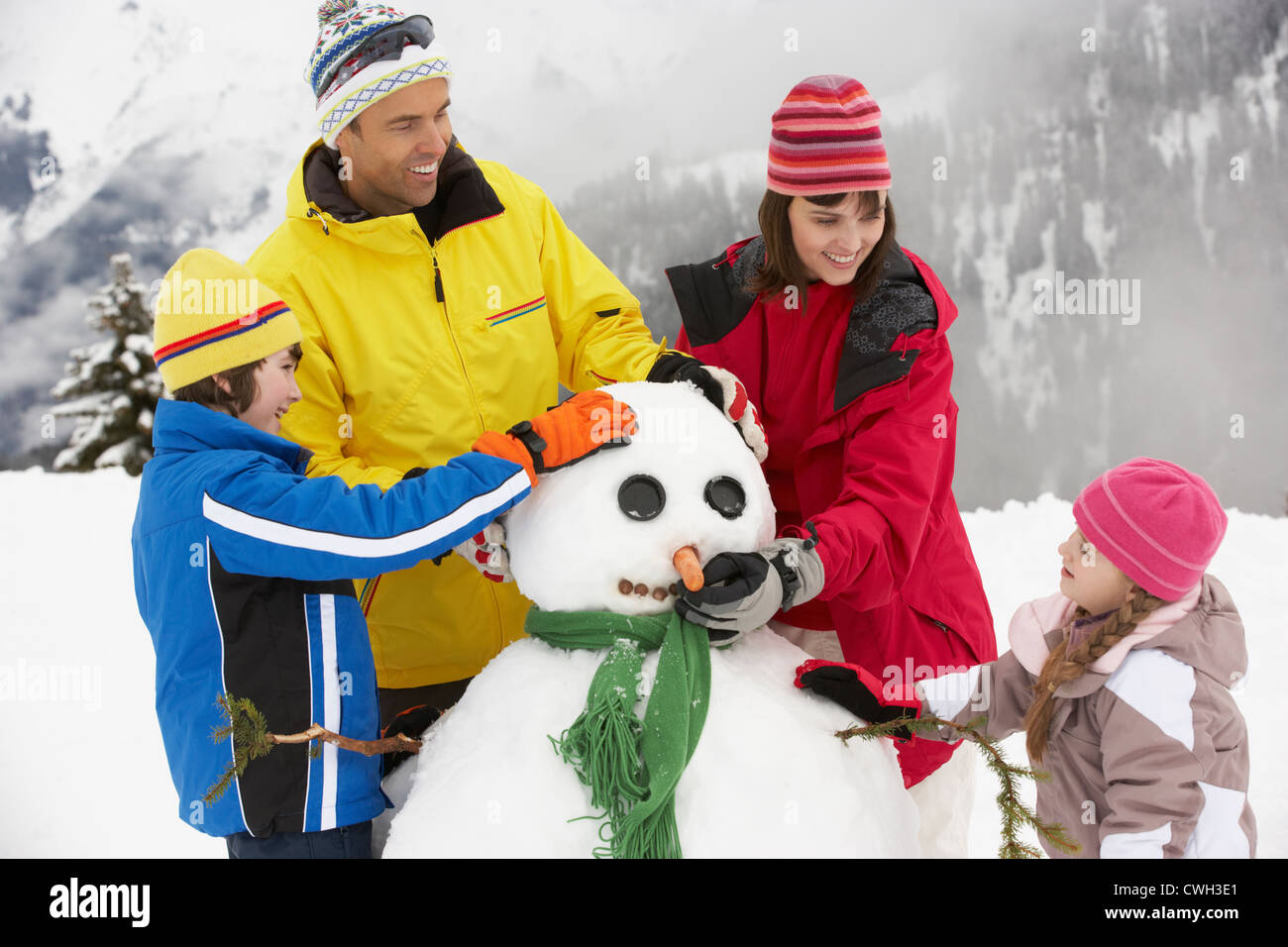 Familie Gebäude Schneemann auf Ski-Urlaub In Bergen Stockfoto
