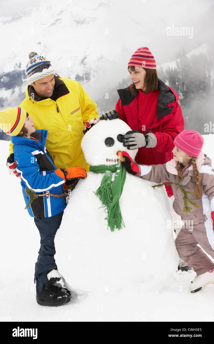 Familie Gebäude Schneemann auf Ski-Urlaub In Bergen Stockfoto
