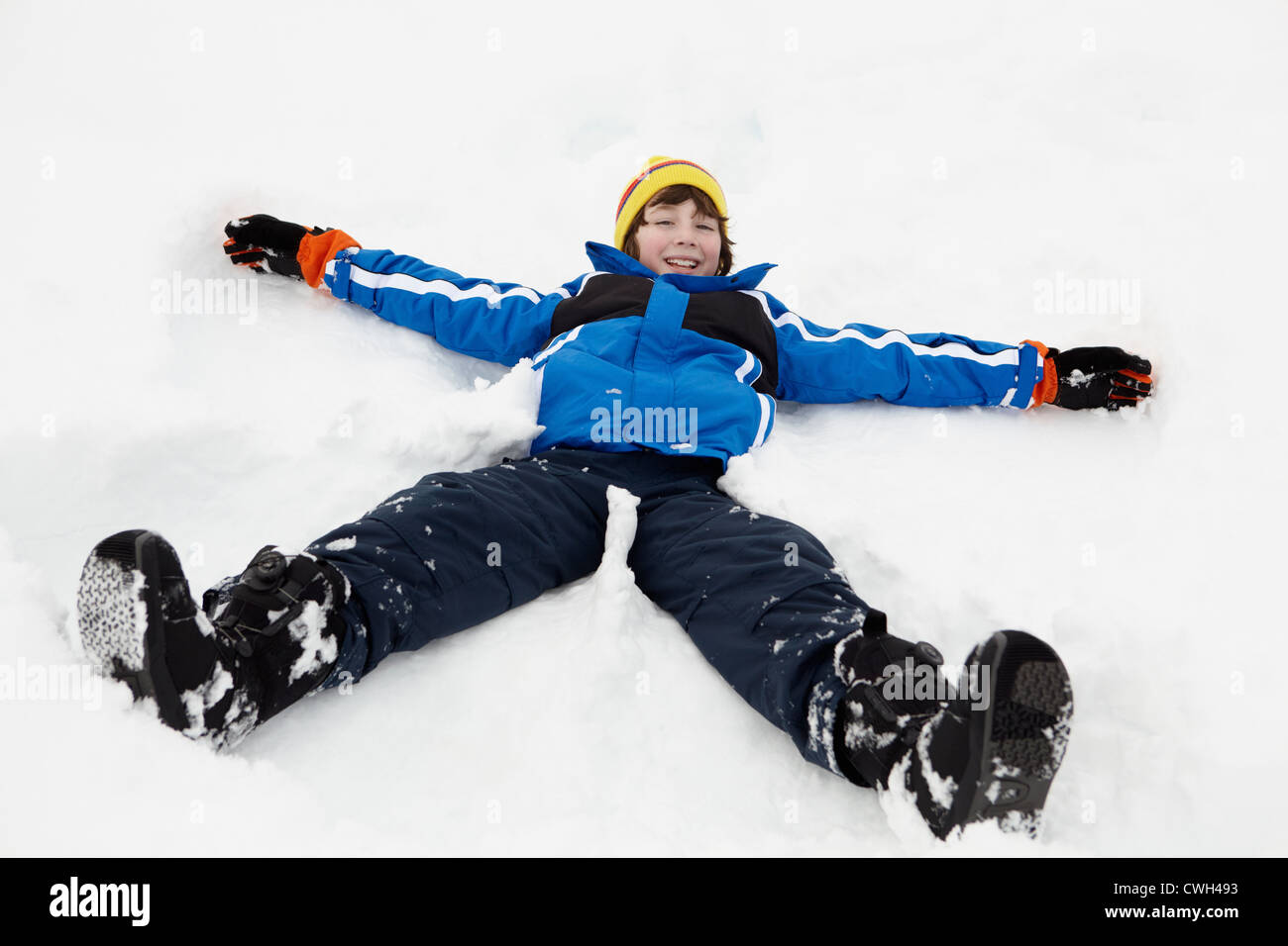 Kleiner Junge macht Schneeengel am Hang Stockfoto