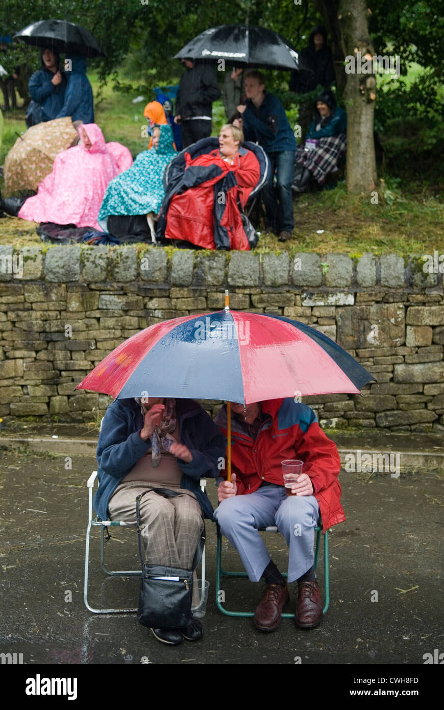 August Sommer Regen UK. Besucher sehen Morris-Männer beim Tanzen während eines Regensturms, der unter ihren Regenschirmen Schutz sucht. Uppermill Saddleworth Lancashire HOMER SYKES der 2012 2010er Jahre Stockfoto
