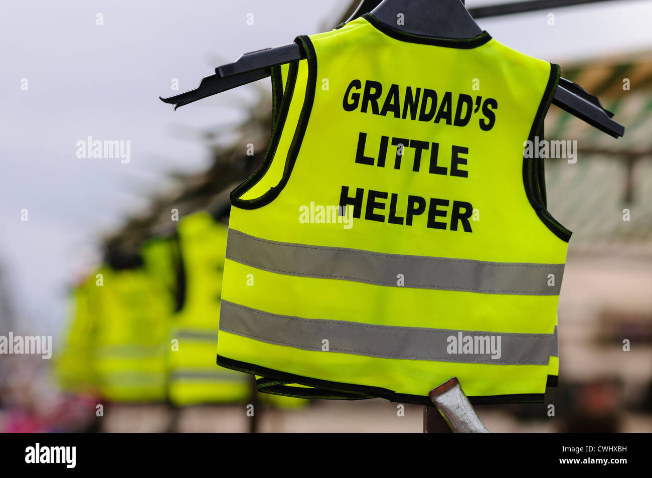 Warnwesten mit Slogan "Opas kleine Helfer" zum Verkauf an einem Marktstand Stockfoto