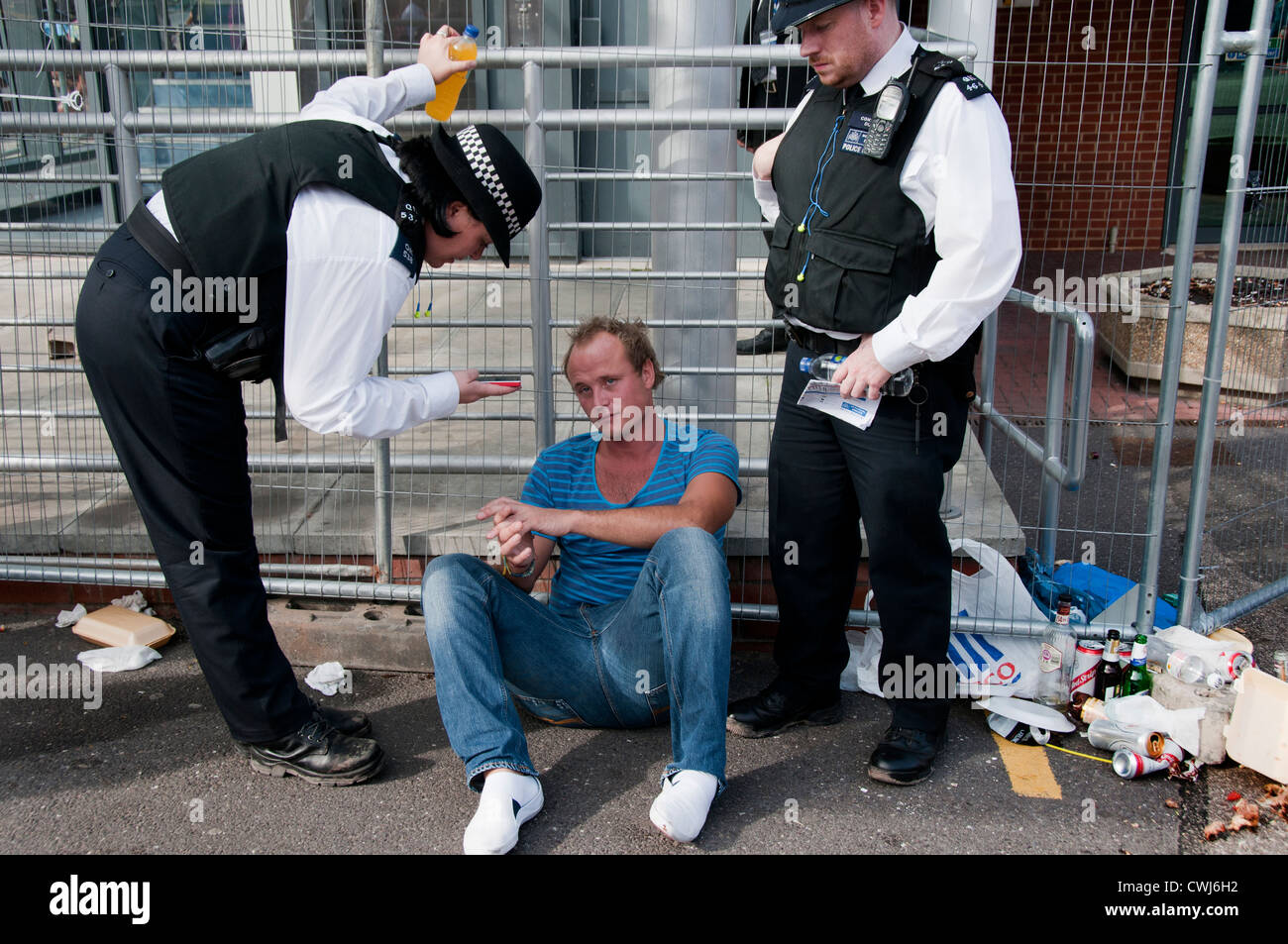 Junger Mann, der Alkohol & Party in Notting Hill Karneval übertrieb befragt & geholfen durch die Polizei Stockfoto