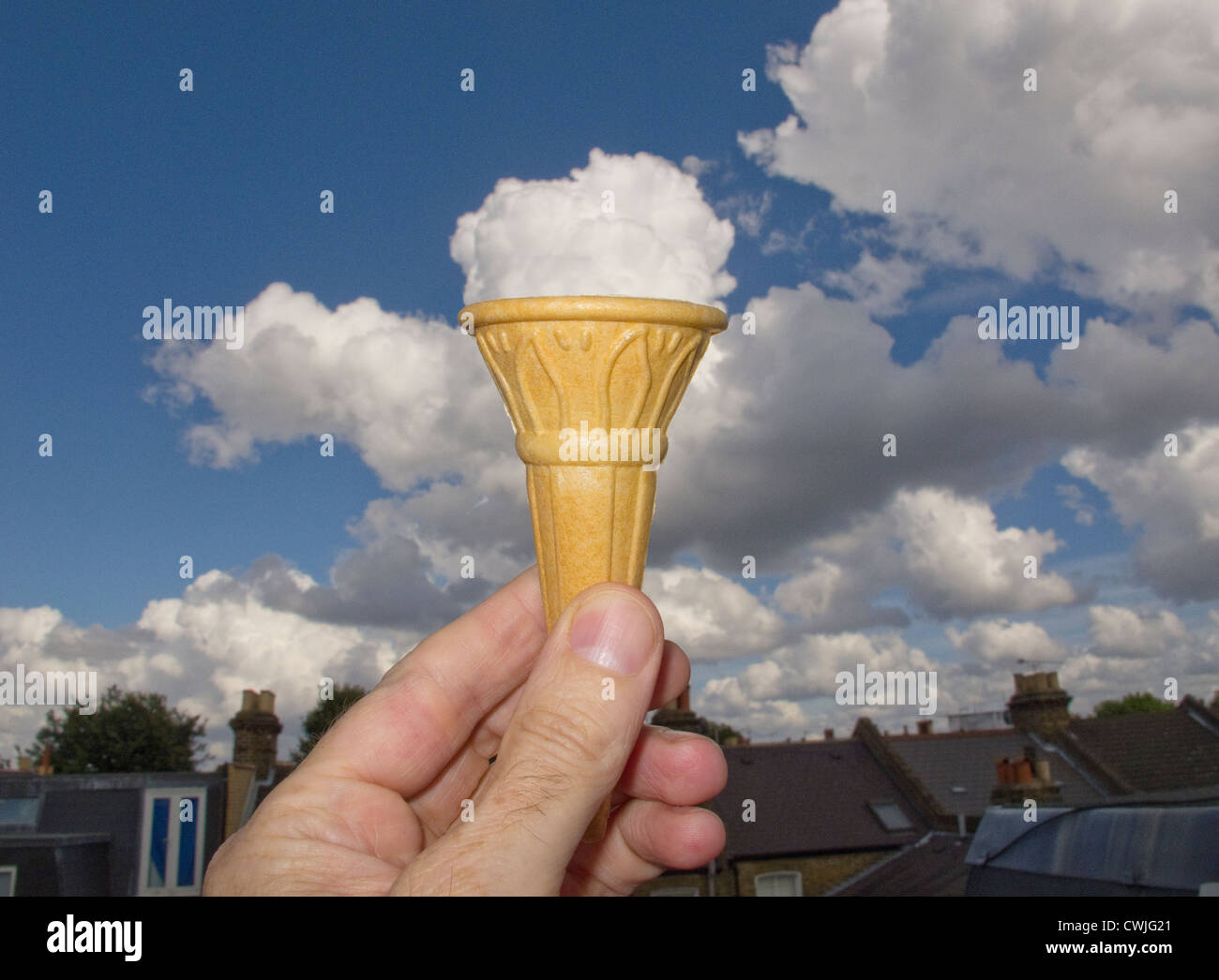 Eine Hand hält ein Eis mit der Cloud hinter sah aus wie es ist Eis Stockfoto
