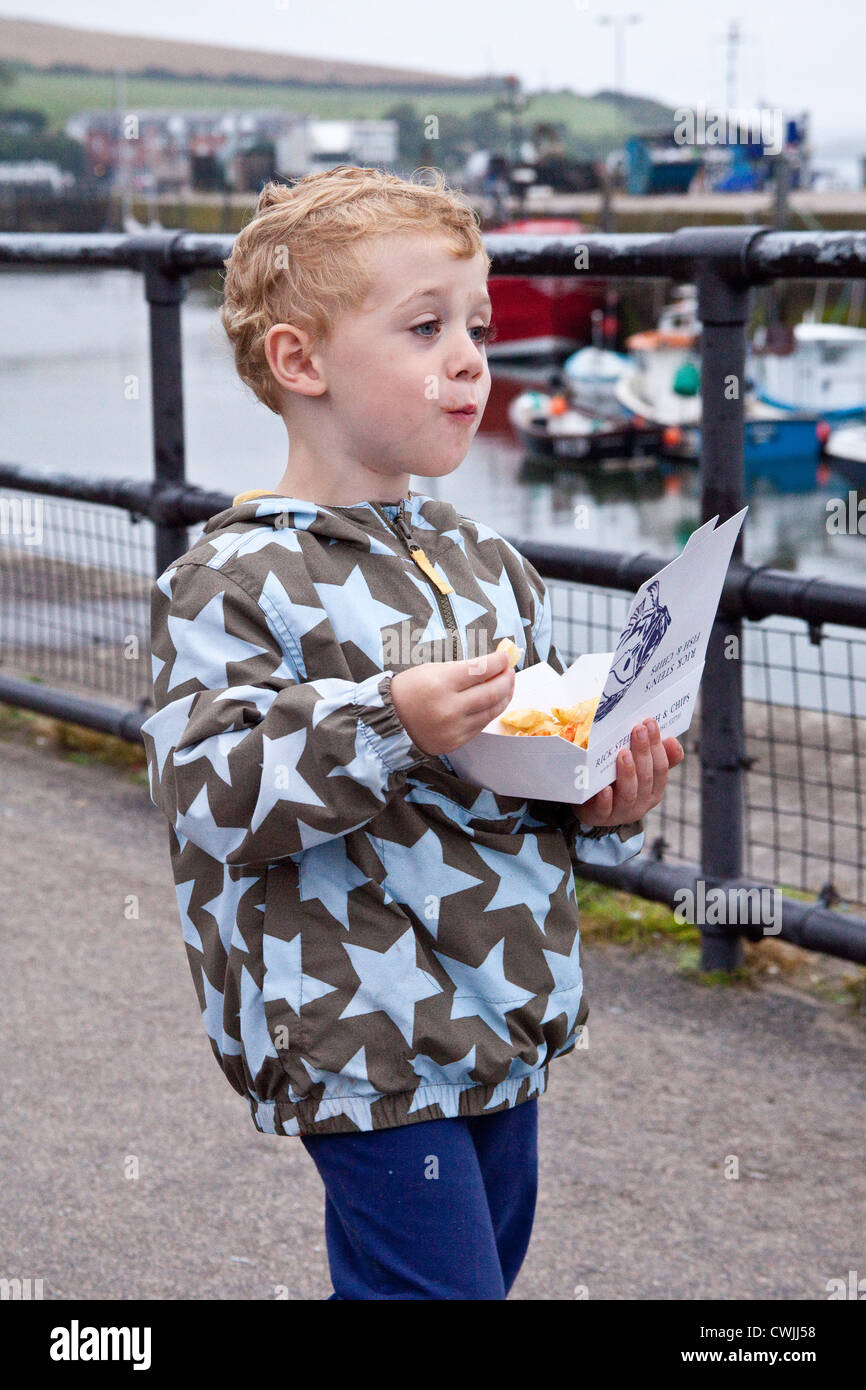 Drei Jahre alter Junge Essen Fisch und Chips von Rick Steins Fish &amp; Chips-Shop, Padstow, Cornwall, England, Vereinigtes Königreich. Stockfoto