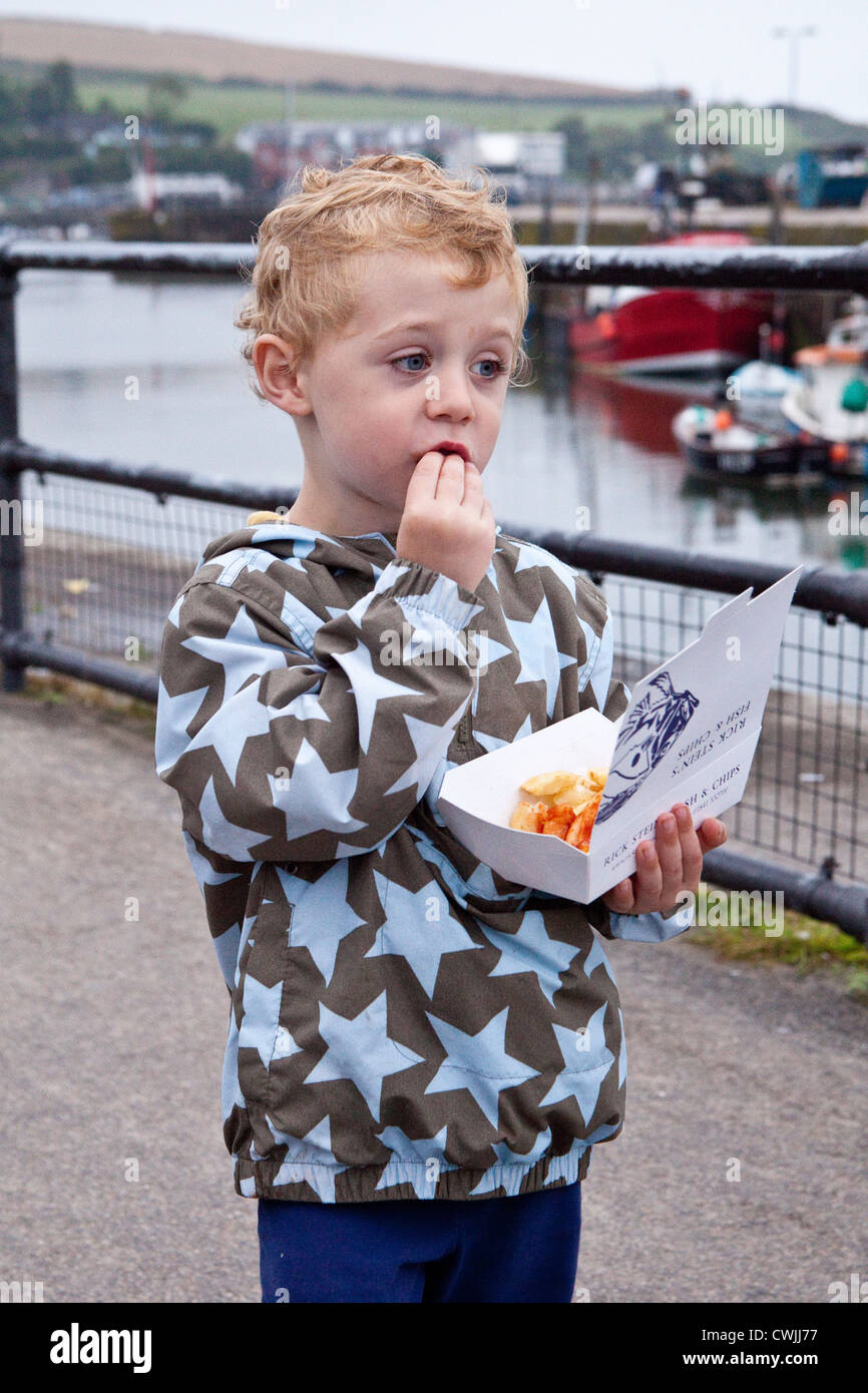 Drei Jahre alter Junge Essen Fisch und Chips von Rick Steins Fish &amp; Chips-Shop, Padstow, Cornwall, England, Vereinigtes Königreich. Stockfoto