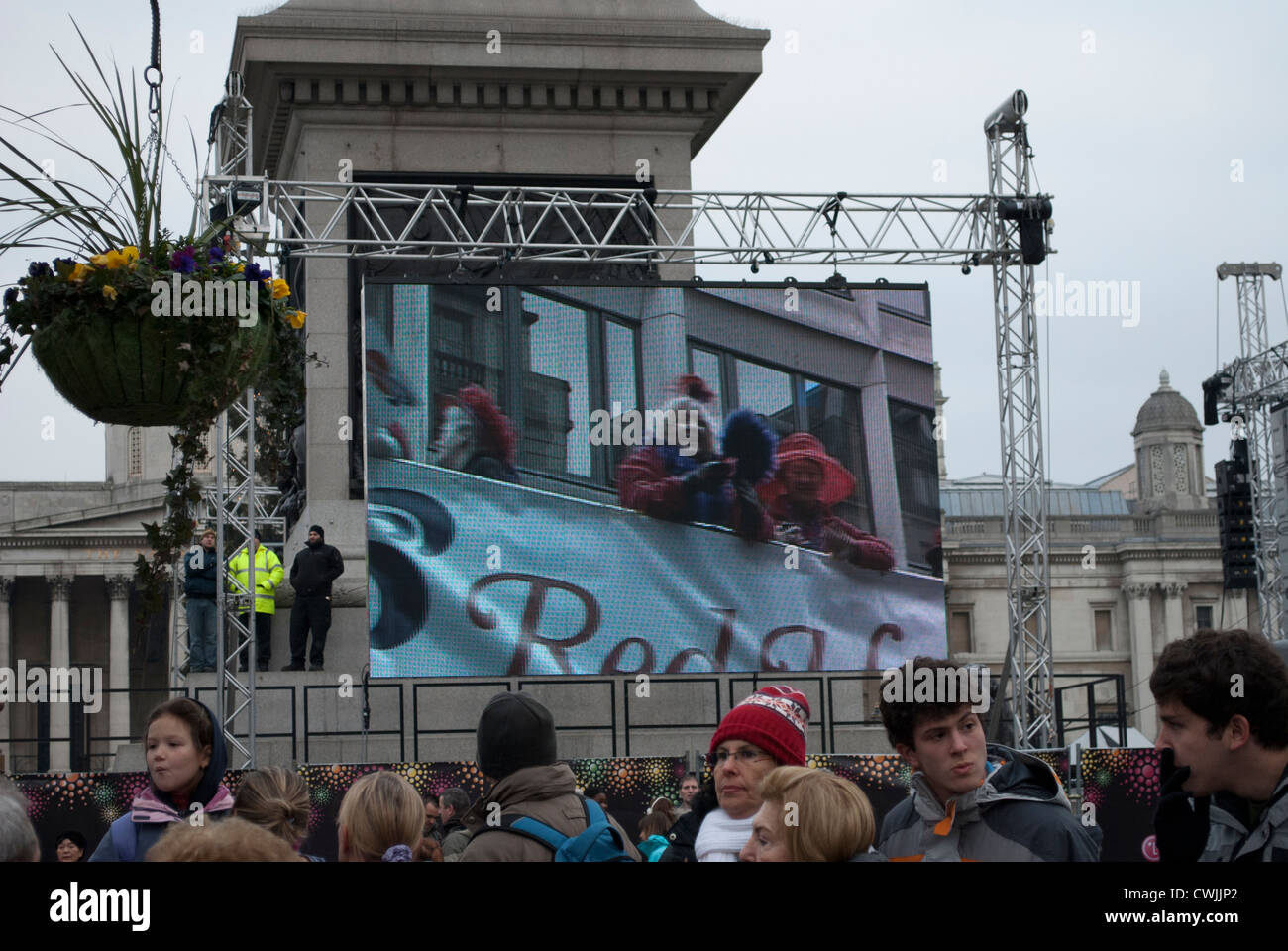 Rot Hut Vereinsmitglieder auf eine offene gekrönt Bus am Bildschirm auf dem Trafalgar Square zeigt die New Years Day parade Stockfoto