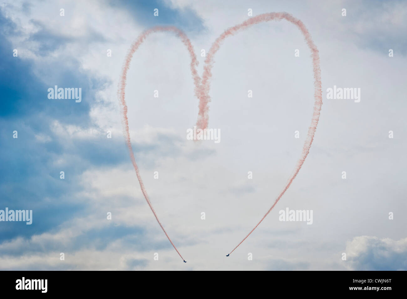 Rosa rauch Spuren von einer Antenne Kunstflug Team bilden eine liebe herz Symbol in den Himmel anzeigen. Konzept Bild Stockfoto