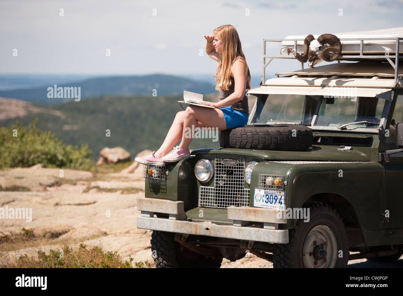 Junge Frau mit Journal auf SUV Motorhaube, Bar Harbor, Maine, USA Stockfoto