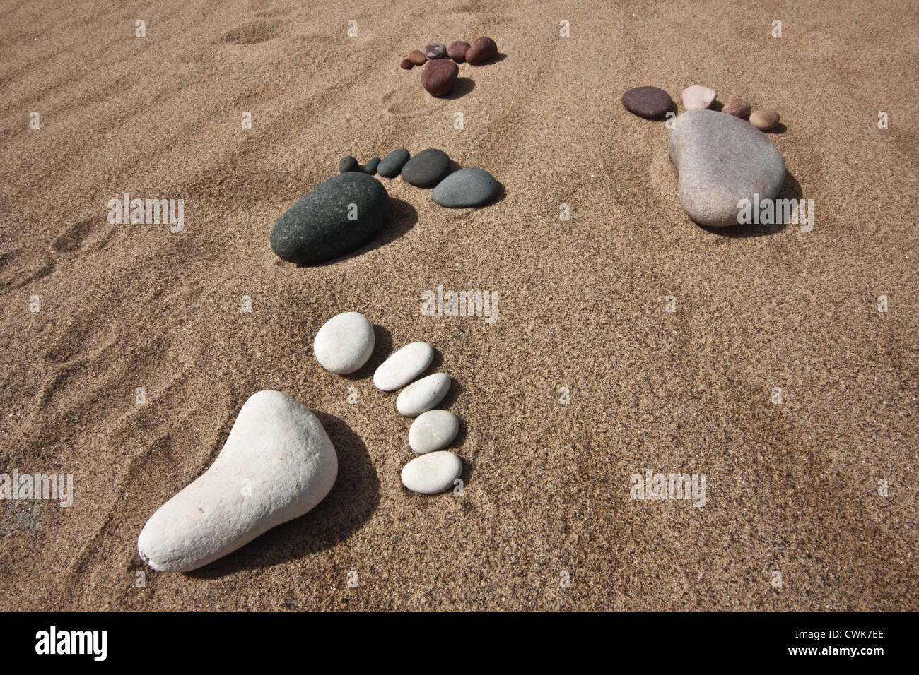verschiedene farbige Spuren aus Kieselsteinen gemacht spazieren Sie vereint auf einen sandigen Strand Stockfoto