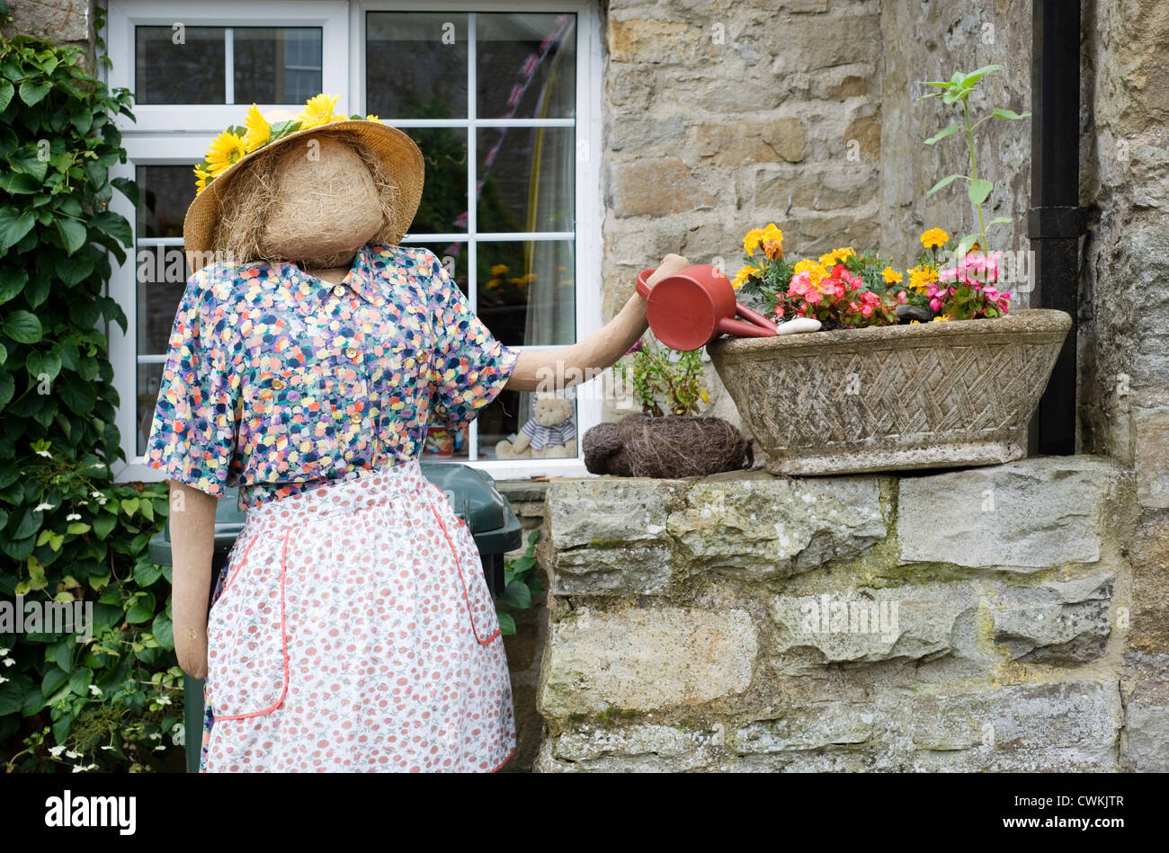Vogelscheuche Kettlewell Festival zeigt eine Frau, die Blumen gießen Stockfoto