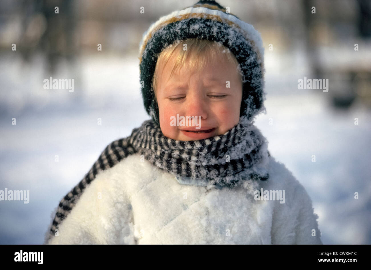 Ein kleiner Junge gebündelt gegen das Winterwetter ist unglücklich über die kalten Temperaturen, wenn er ging hinaus, um im Schnee zu spielen. Stockfoto