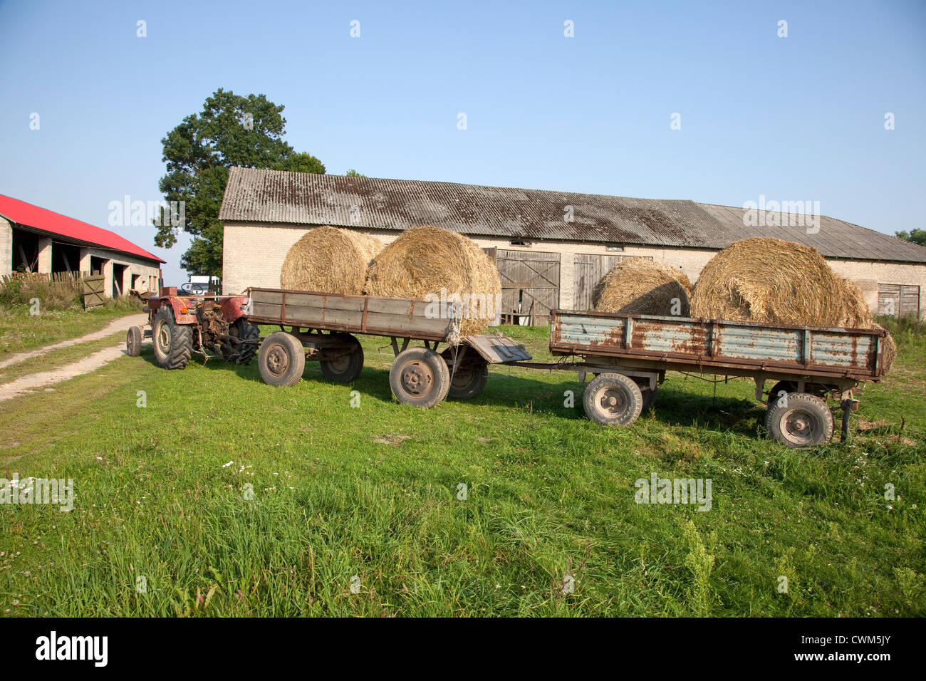 Traktor und Bauernhof Wagen beladen mit großen runden Heu Bails bereit, in der Scheune geladen werden. Zawady Zentralpolen Stockfoto