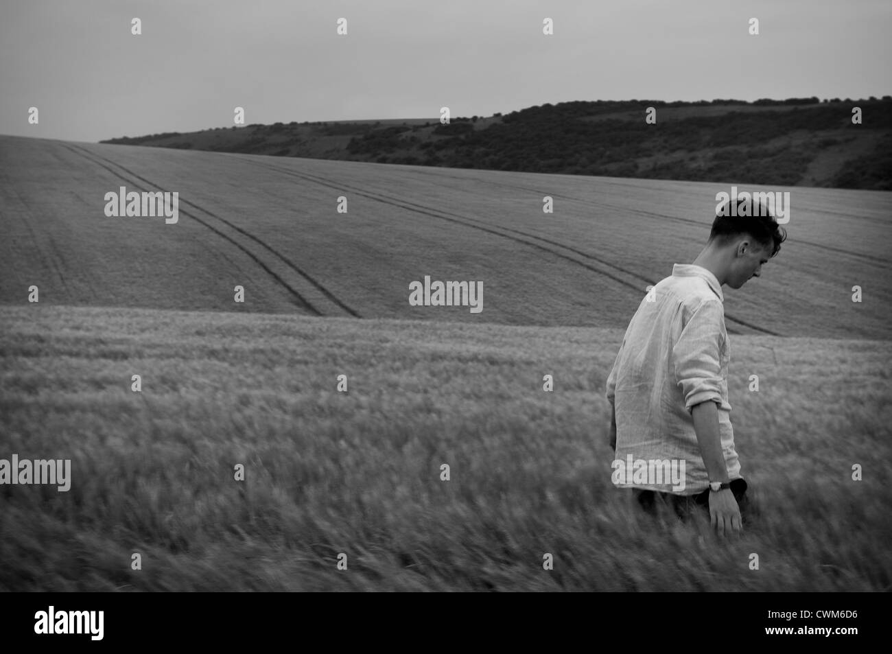Junger Mann zu Fuß durch ein Weizenfeld in East Sussex, UK Stockfoto