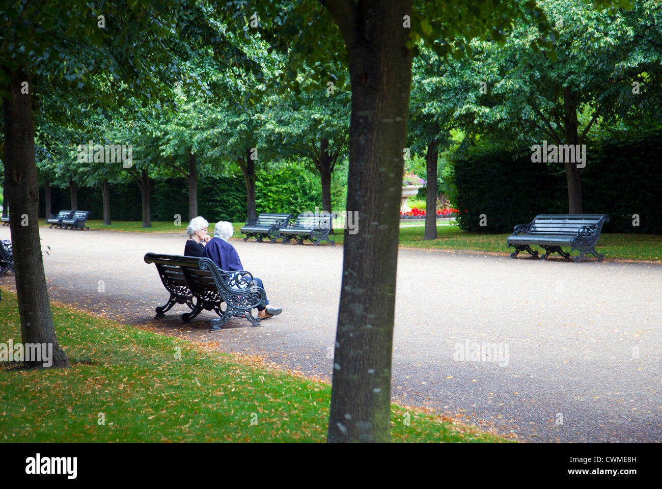 Zwei ältere Damen sitzen auf Bank auf breiten Walk im Regents Park in London UK Stockfoto