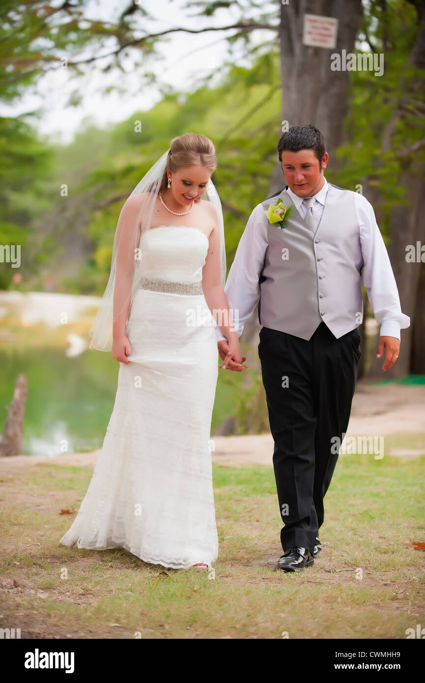 Braut und Bräutigam gehen Hand in Hand in natürlicher Umgebung bei ihrer Hochzeit. Stockfoto