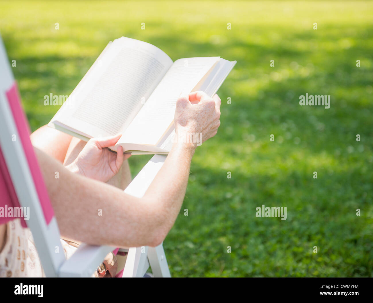 USA, New Jersey, Mendham, Frau sitzen auf Liegestuhl und Buch Stockfoto